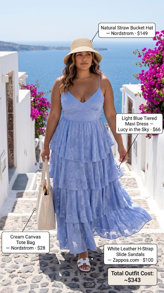 Curvy woman in light blue tiered maxi dress with straw bucket hat, white sandals, and canvas tote on Greek island