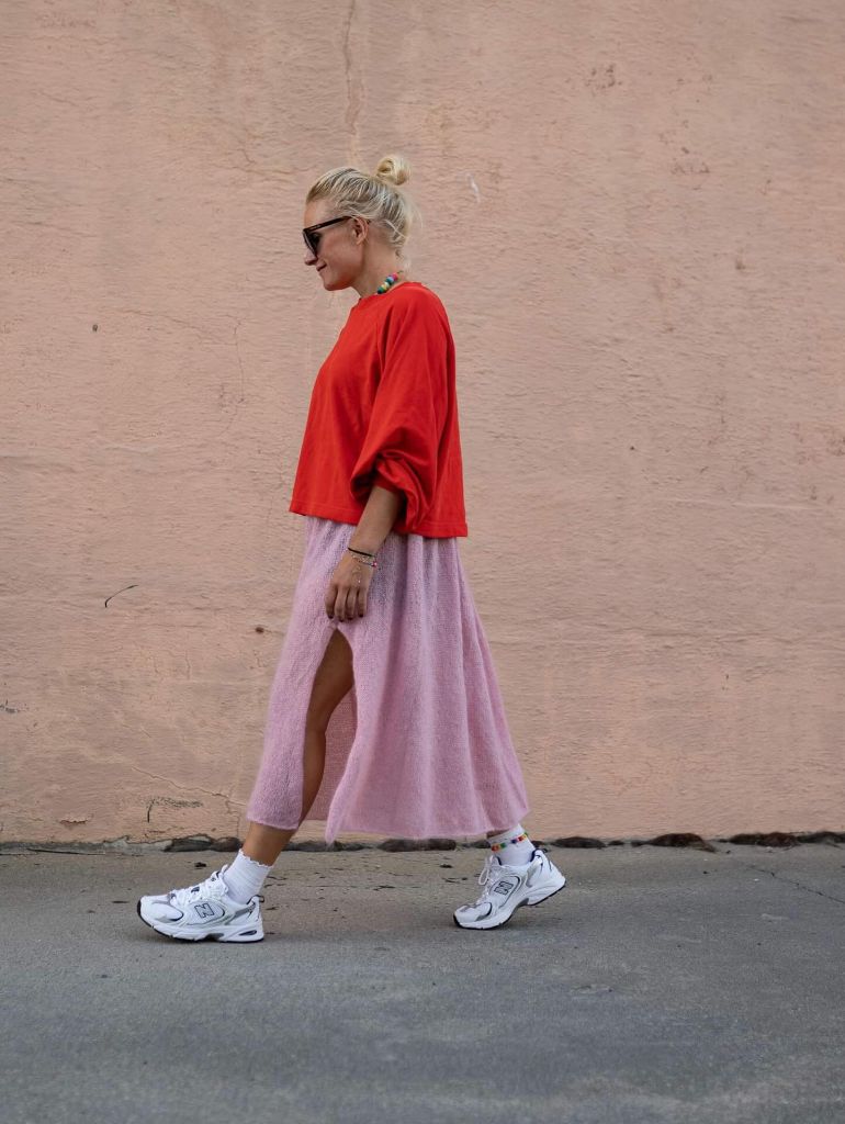 Red oversized t-shirt with pink fuzzy midi skirt and white New Balance sneakers