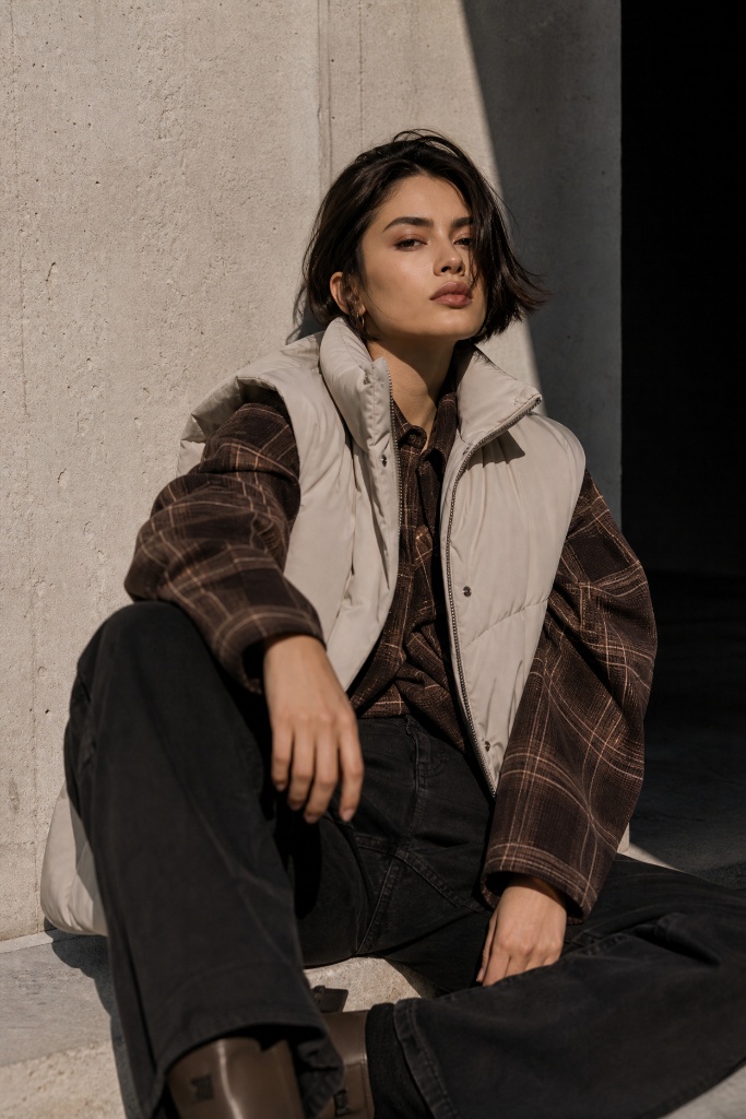 Cream puffer vest over brown plaid flannel with black jeans