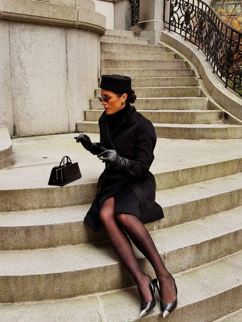 Black coat with pillbox hat, leather gloves, and metallic heels on stone steps