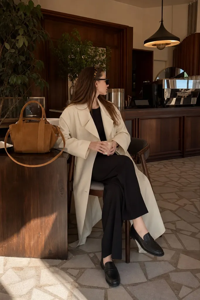 Cream trench coat with black outfit and loafers