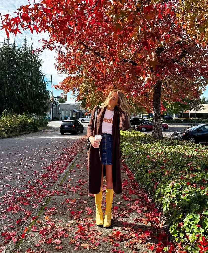 Long burgundy teddy coat over graphic tee and denim mini skirt with yellow boots