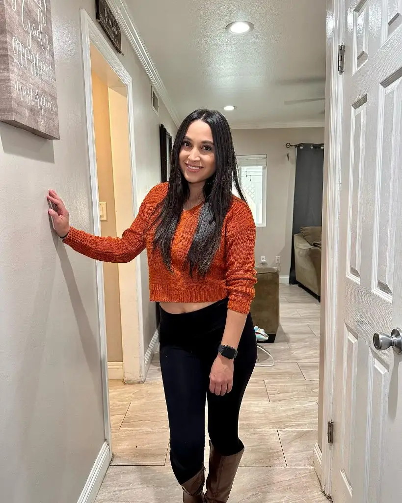 Cropped burnt orange sweater with black leggings and brown knee-high boots