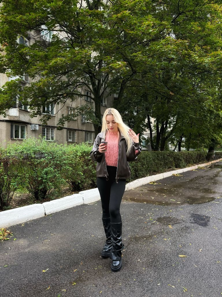 Pink knit sweater under black leather bomber jacket with black leggings and tall boots