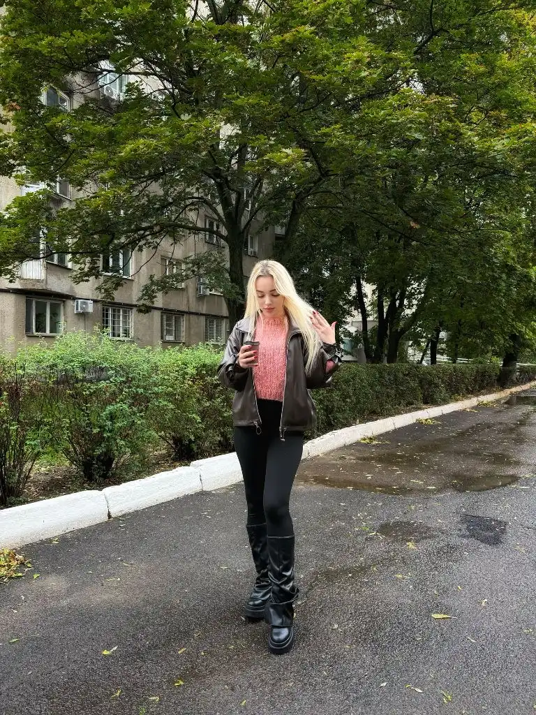 Pink knit sweater under black leather bomber jacket with black leggings and tall boots