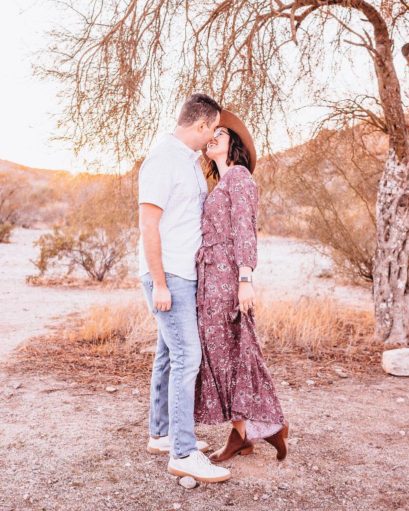 Couple in desert setting with woman in floral maxi dress and wide-brim hat