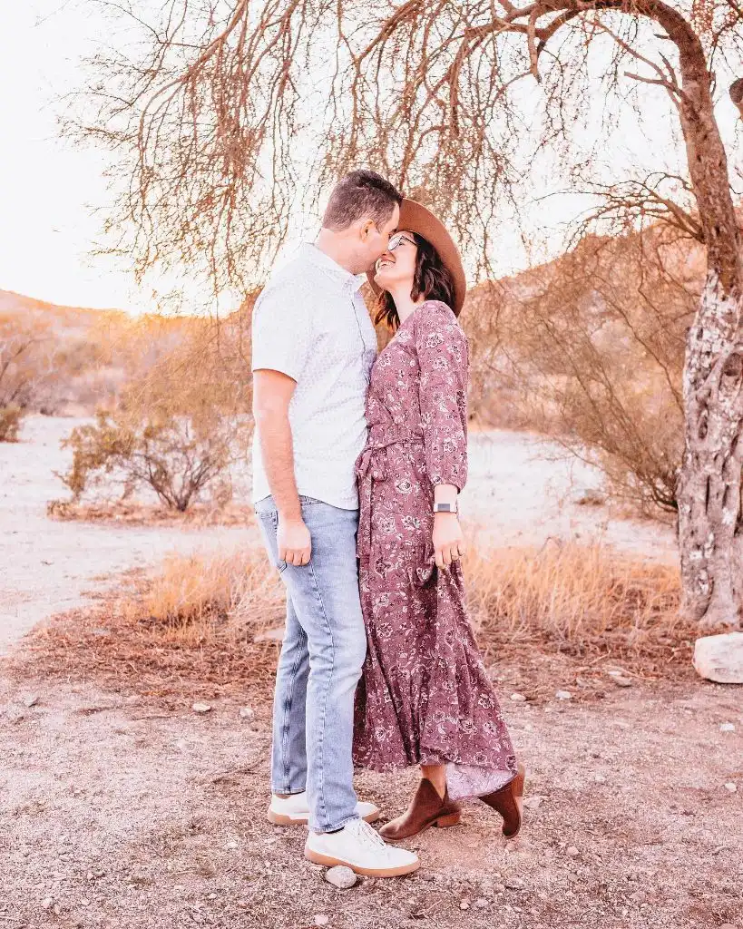 Couple in desert setting with woman in floral maxi dress and wide-brim hat