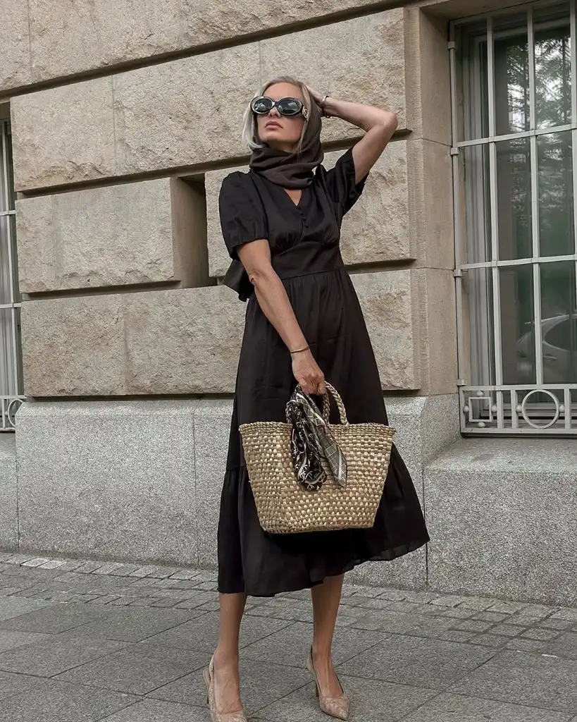 Black puff-sleeve midi dress with brown headscarf, oversized sunglasses, woven straw tote, and nude pointed heels