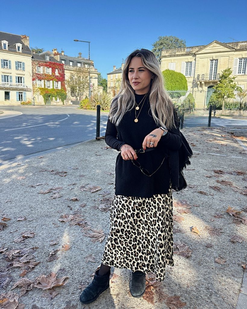 Black ribbed sweater with leopard midi skirt and black ankle boots in French town square