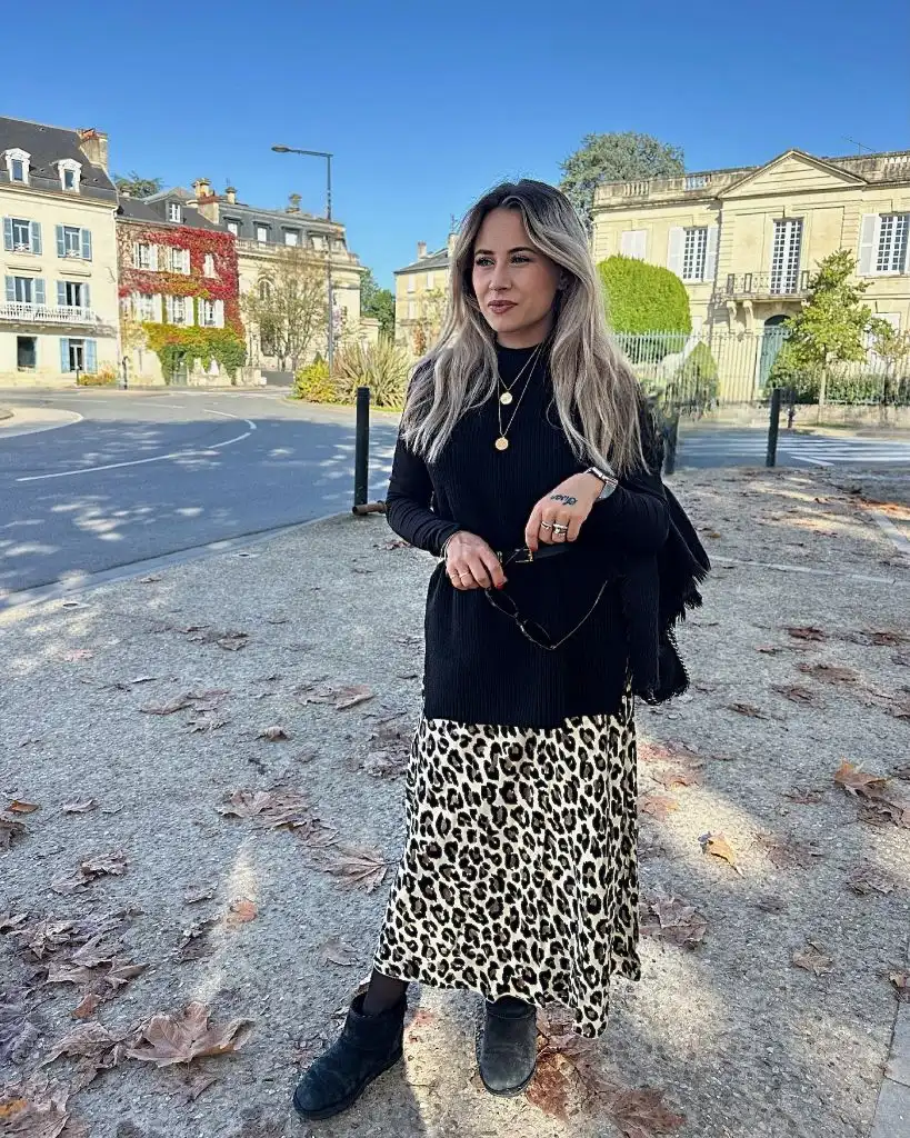 Black ribbed sweater with leopard midi skirt and black ankle boots in French town square