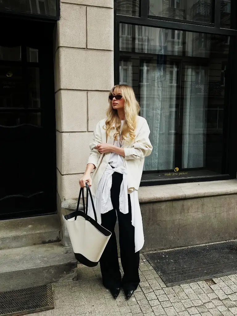 Cream trench coat with black wide-leg trousers, pointed boots, and oversized tote