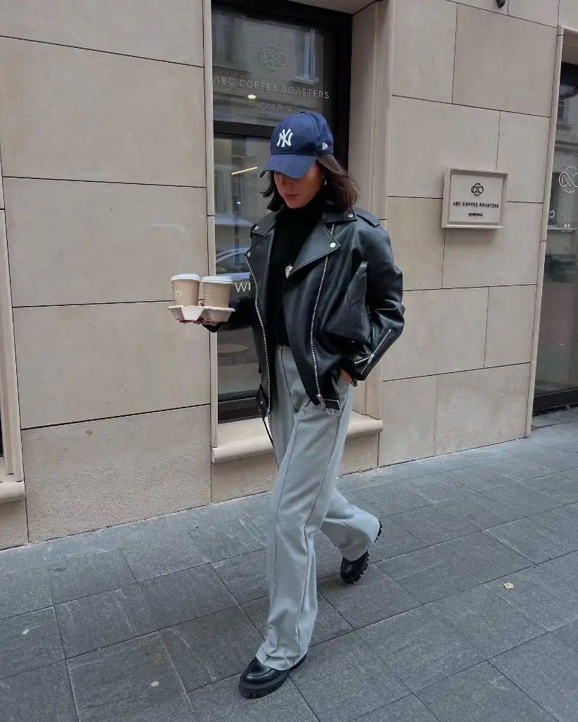 Fall leather moto jacket with grey trousers and NY cap