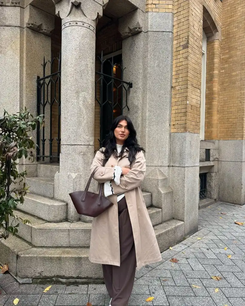 Beige trench coat with brown trousers and burgundy bag