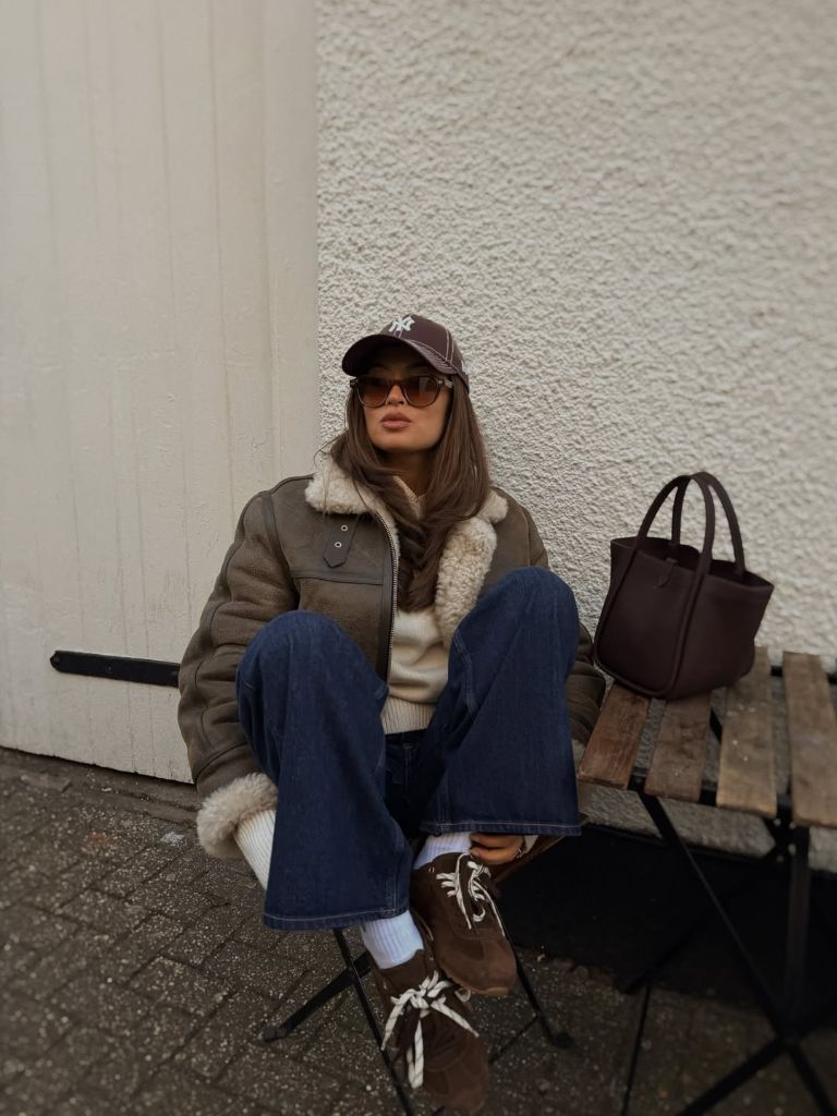 Olive shearling jacket with jeans, baseball cap, and brown tote