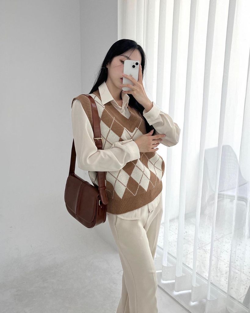 Brown and cream argyle sweater vest over white collared shirt with cream trousers and brown leather shoulder bag