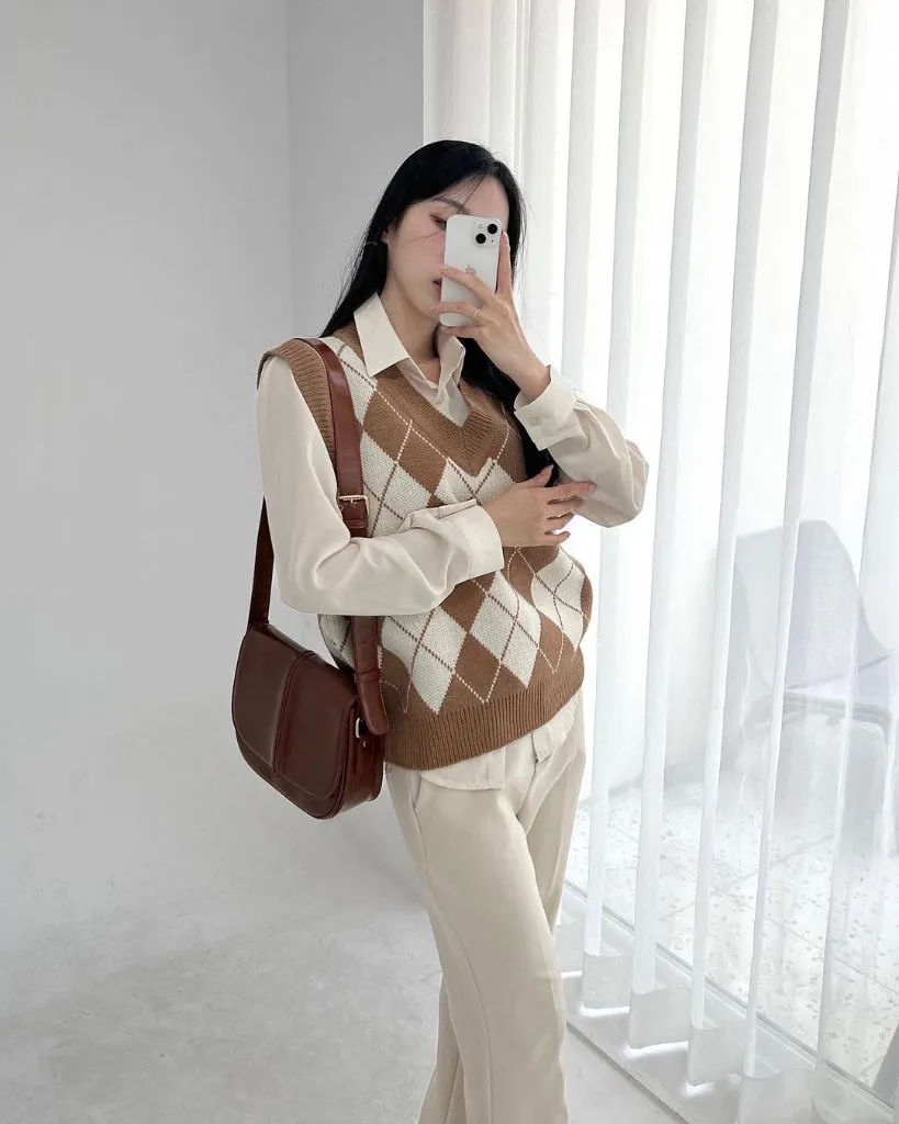 Brown and cream argyle sweater vest over white collared shirt with cream trousers and brown leather shoulder bag