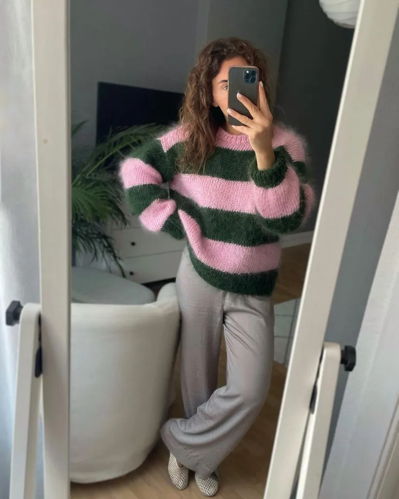 Pink and green striped mohair sweater with beige trousers