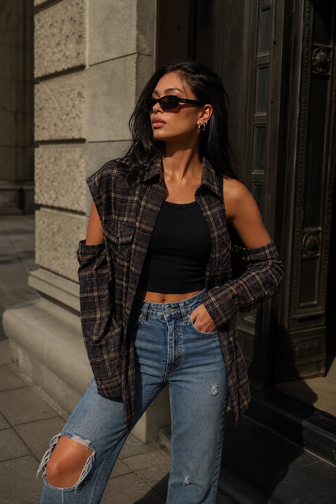 Brown plaid cold-shoulder shirt with black crop top and ripped jeans