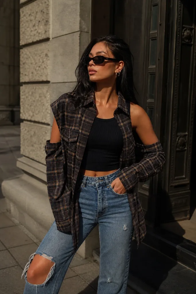 Brown plaid cold-shoulder shirt with black crop top and ripped jeans