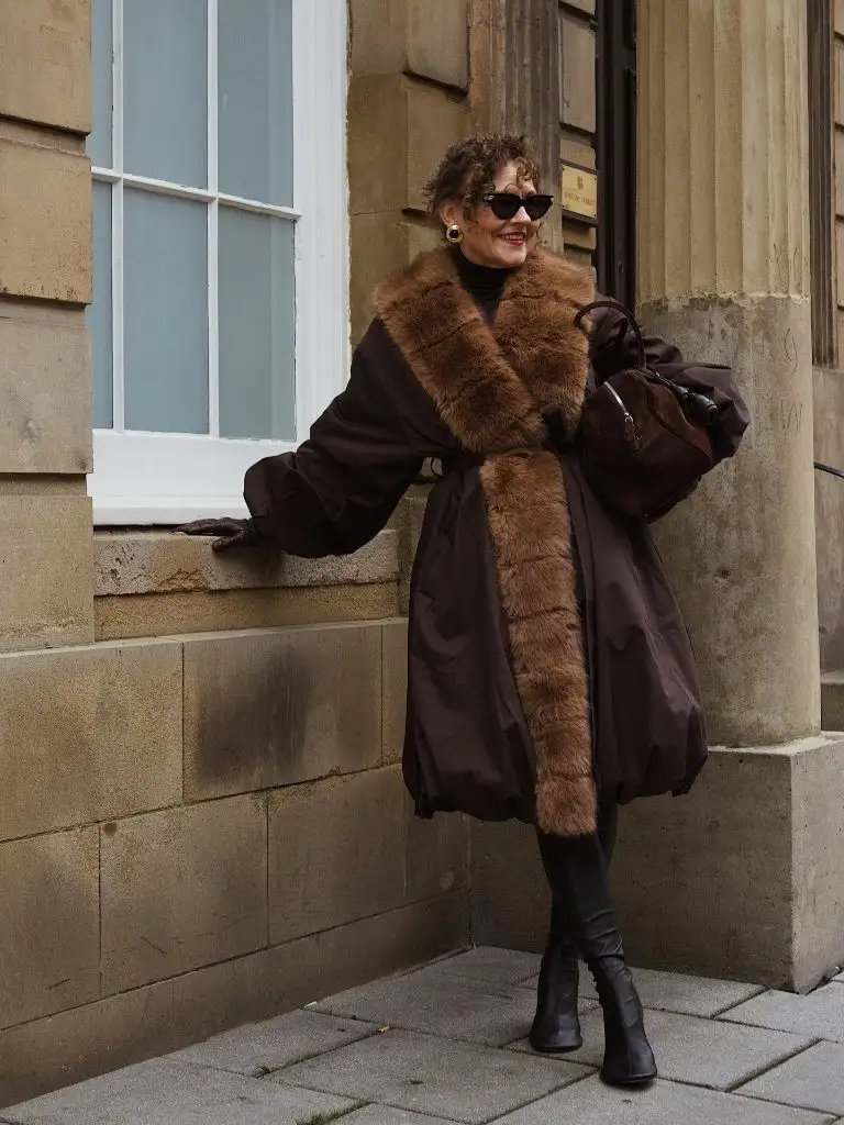 Brown puffer coat with fur trim, leather leggings and black boots