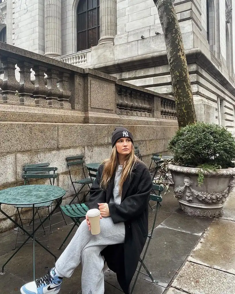 Grey sweatpants, black coat, NY beanie, and Nike sneakers