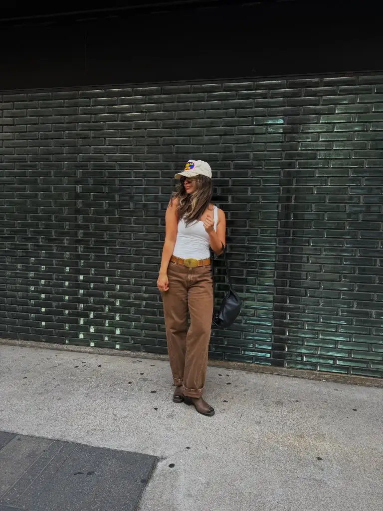 White tank top with brown pants, belt, and cap