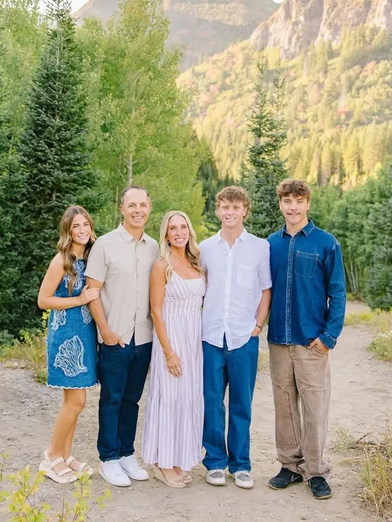 Family of five with teenage children in blue tones standing on mountain trail