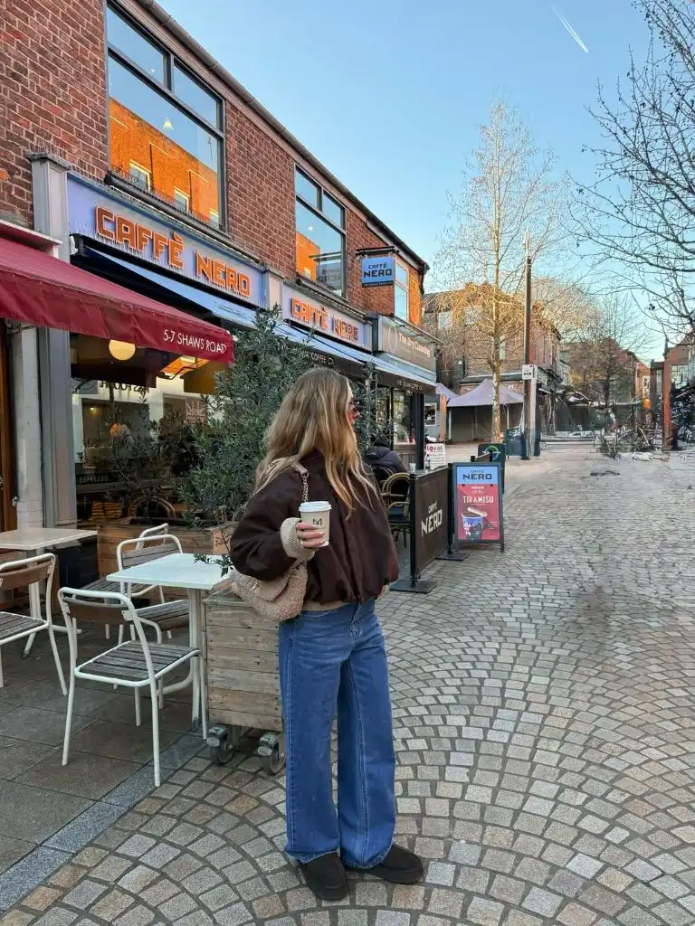 Brown bomber jacket with wide-leg jeans and platform boots outside Caffè Nero