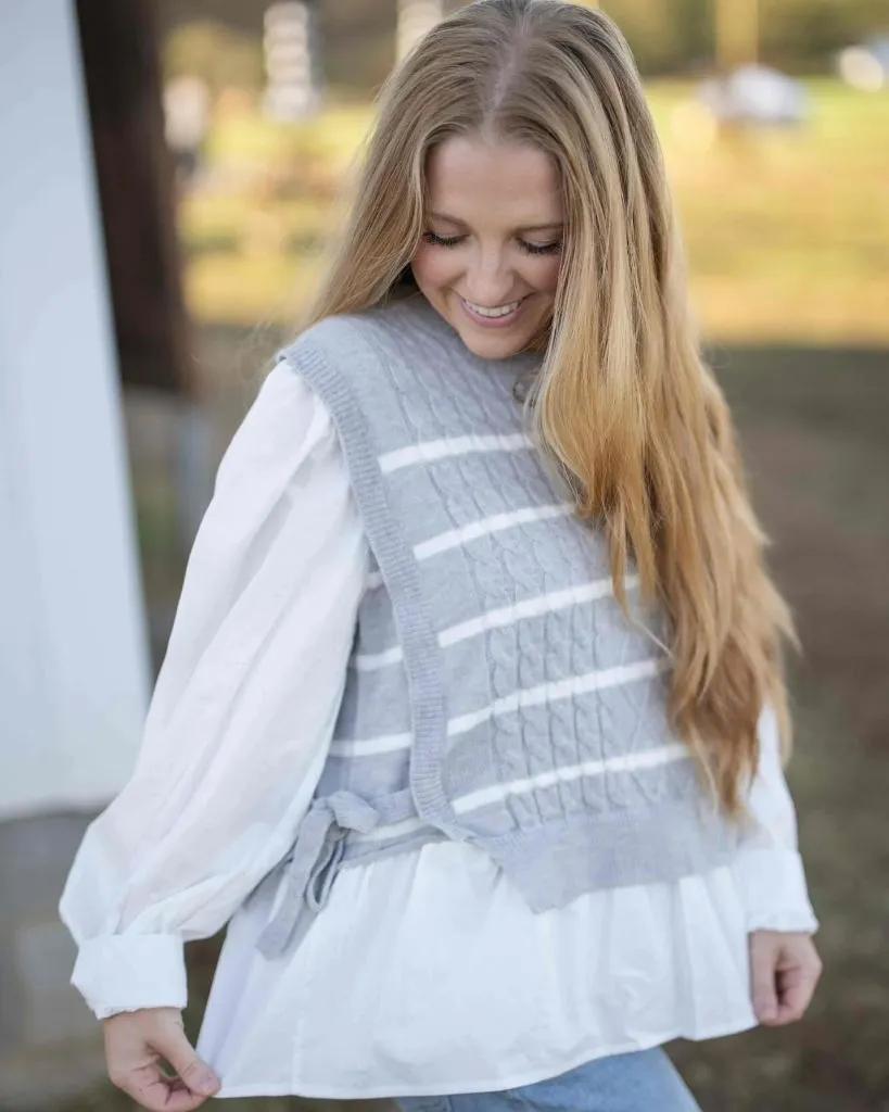 Grey and white striped cable knit vest with tie waist over white ruffled blouse