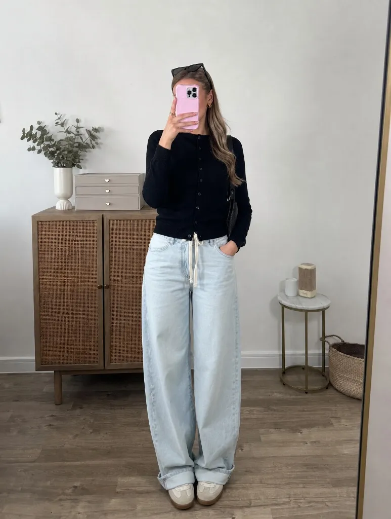 Black button cardigan with very light wide leg jeans and cream sneakers