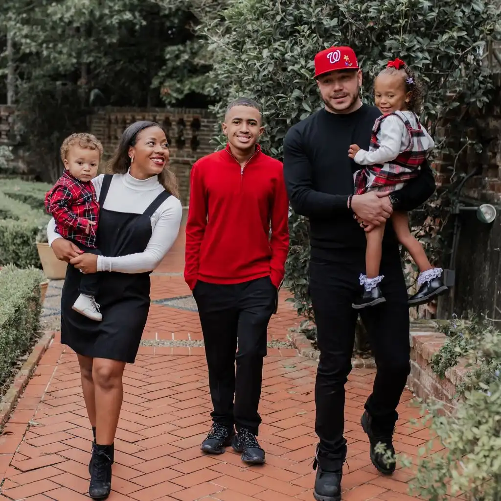 Blended family of five in red and black holiday outfits at brick garden location