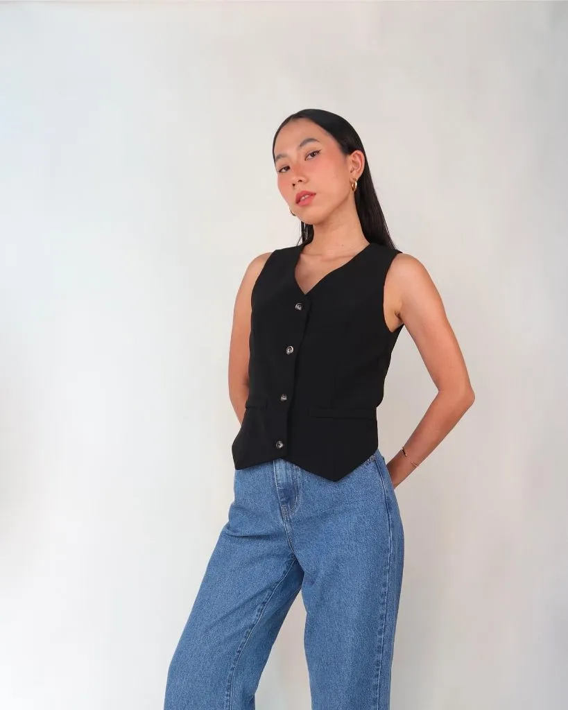 Black V-neck tailored waistcoat with silver buttons worn over light wash high-waisted jeans