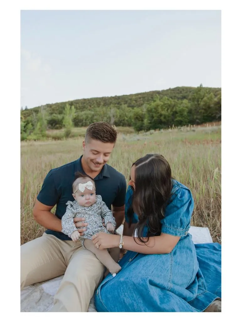 Fall family photo with parents and baby in navy and khaki tones sitting in a field