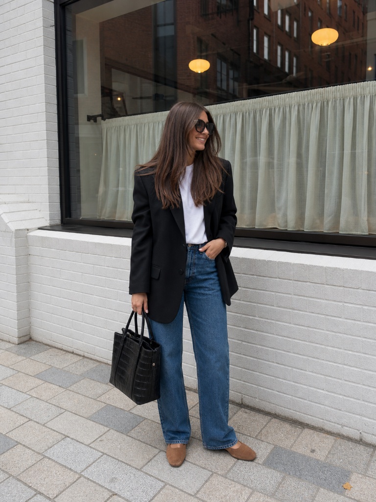 Black blazer with white tee and medium-wash blue jeans with tan mules