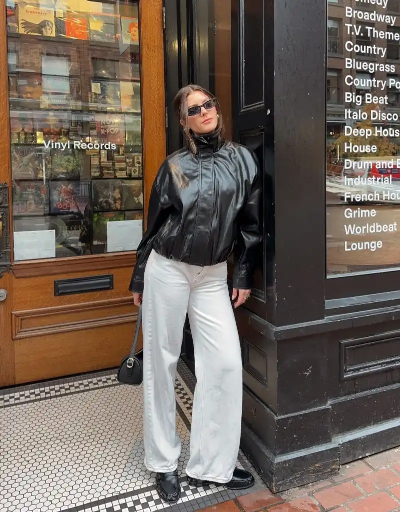 Black leather jacket with white wide-leg pants and black loafers at a record shop