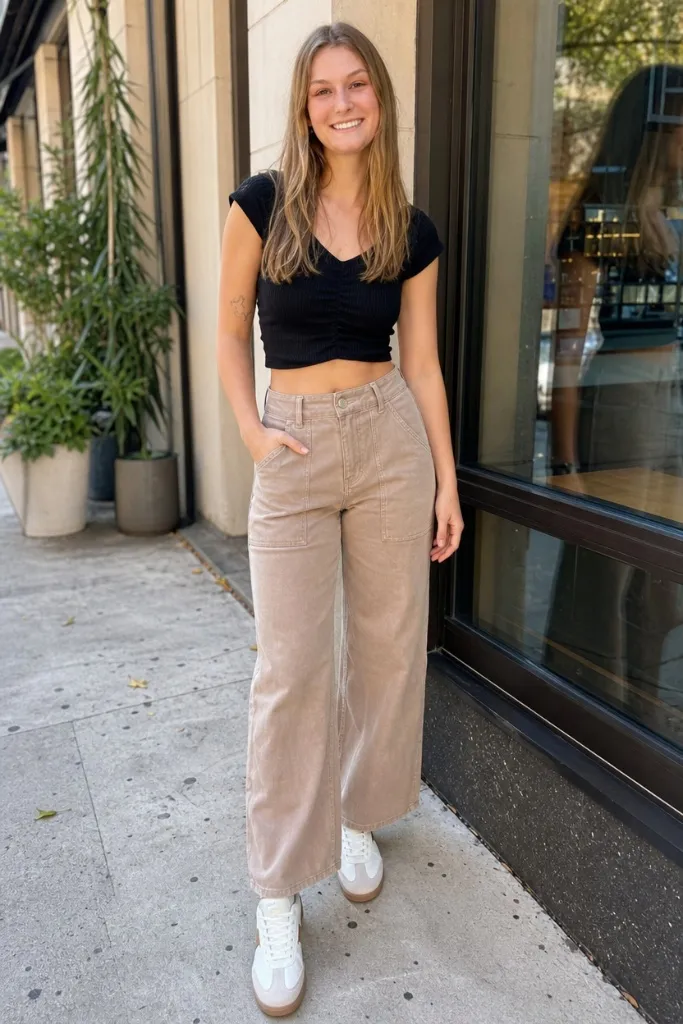 Black crop top paired with tan wide-leg utility pants and white sneakers