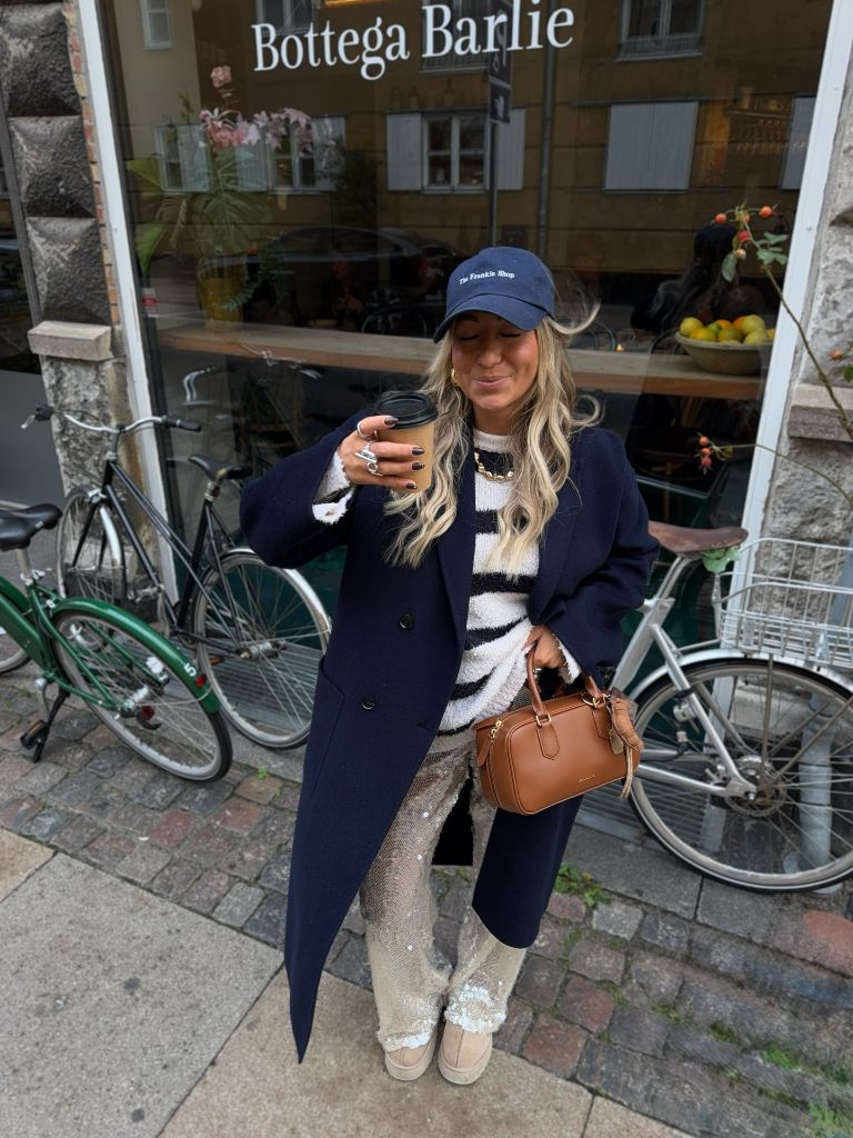 Navy coat with zebra sweater and sequin pants outside Bottega Barlie
