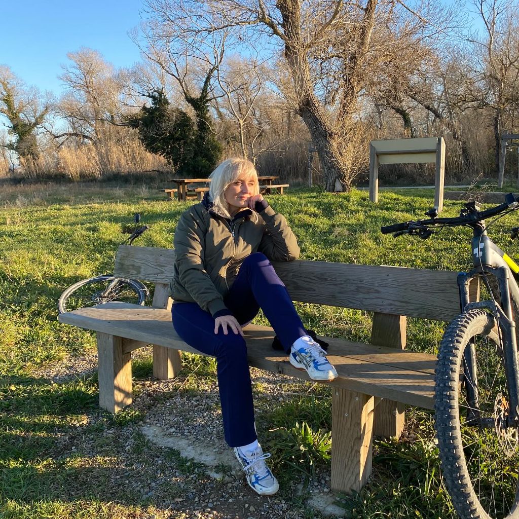Olive bomber jacket with navy joggers and sneakers sitting on a bench