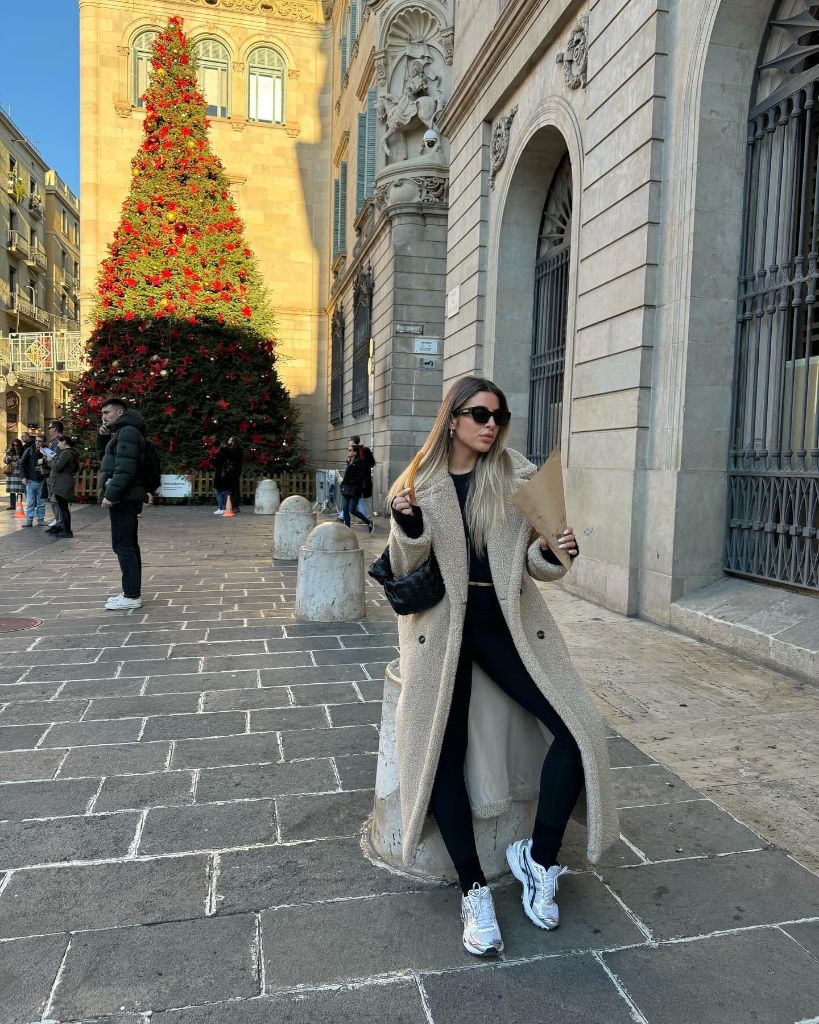 Long beige teddy coat over black outfit with white sneakers