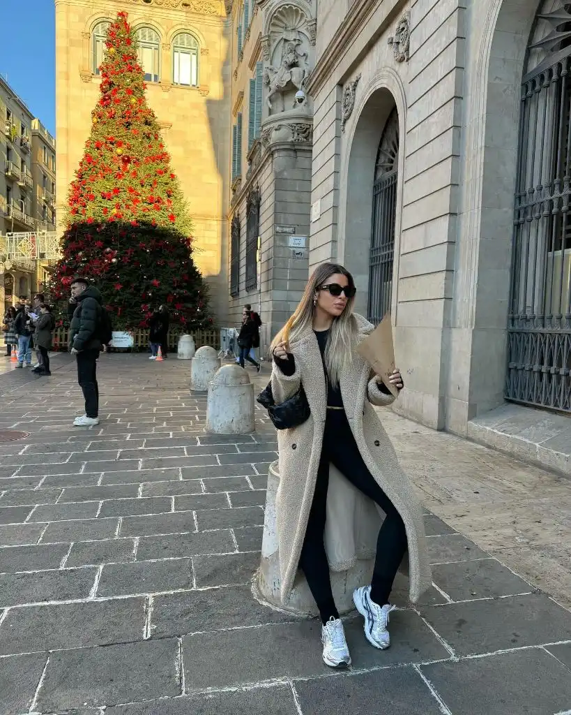 Long beige teddy coat over black outfit with white sneakers