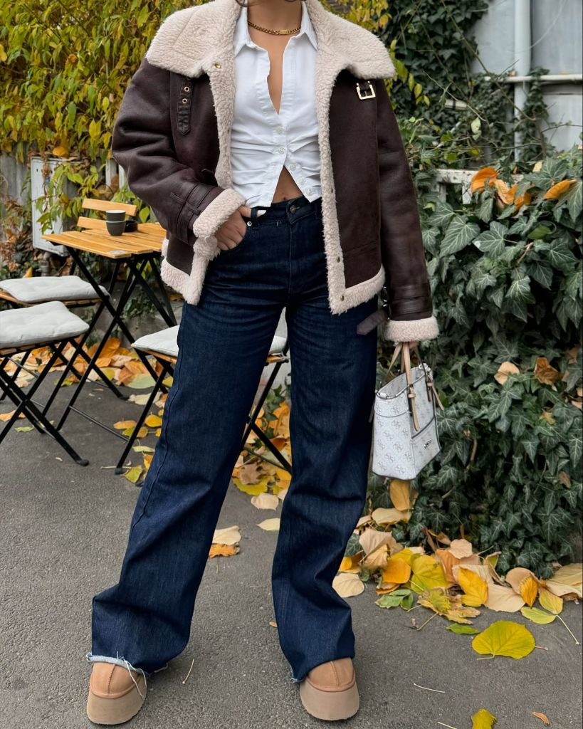 Brown shearling jacket with white shirt and dark wide-leg jeans