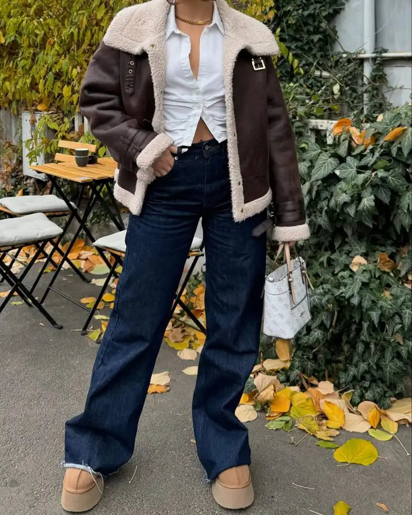 Brown shearling jacket with white shirt and dark wide-leg jeans