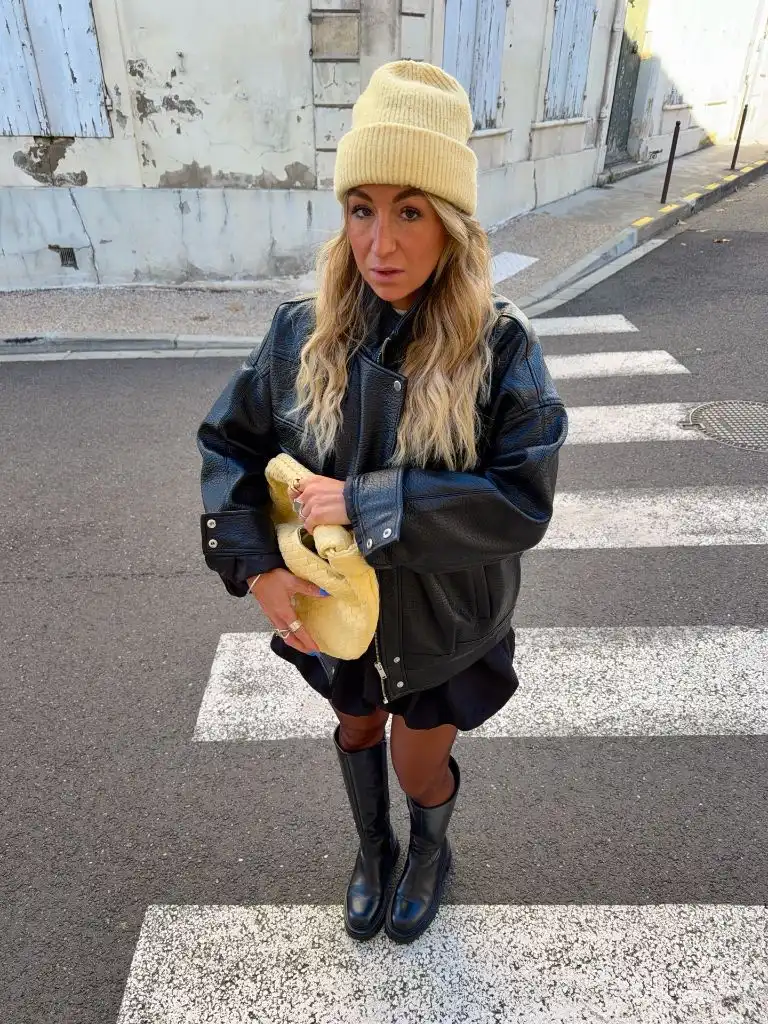Black leather jacket, mini skirt, knee-high boots and yellow beanie