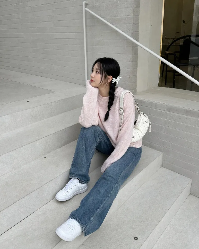 Pink sweater with jeans and white sneakers on steps