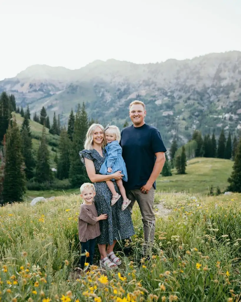 Family of four standing in wildflower mountain meadow in blue and neutral tones