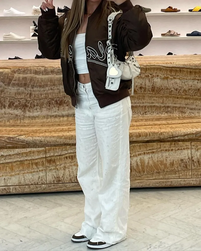 Brown bomber jacket over white tank and white wide-leg pants
