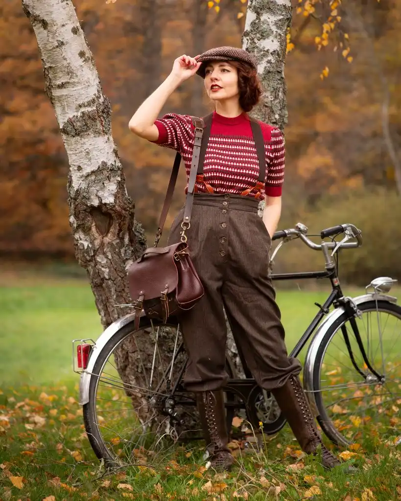 Vintage-inspired Fair Isle knit top with brown wool trousers, suspenders, and a tweed cap beside a bicycle