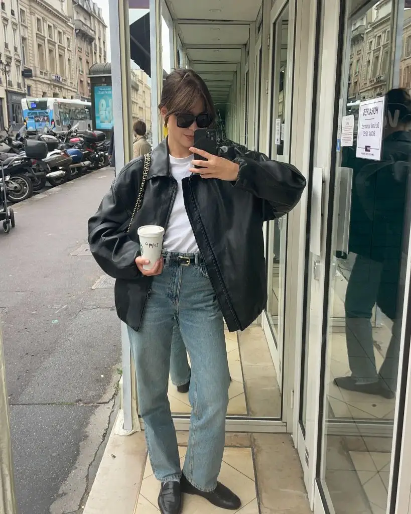 Oversized black leather jacket with white tee and light wash jeans street style