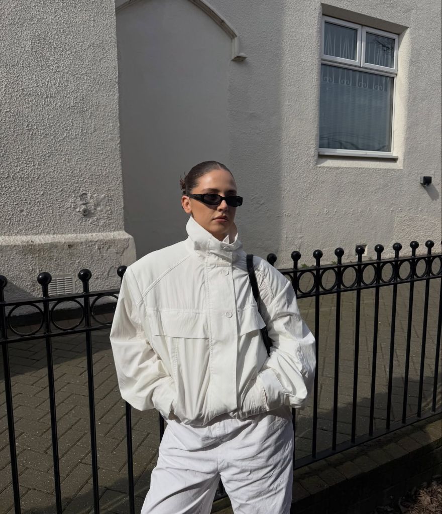 All-white outfit with windbreaker jacket and black sunglasses