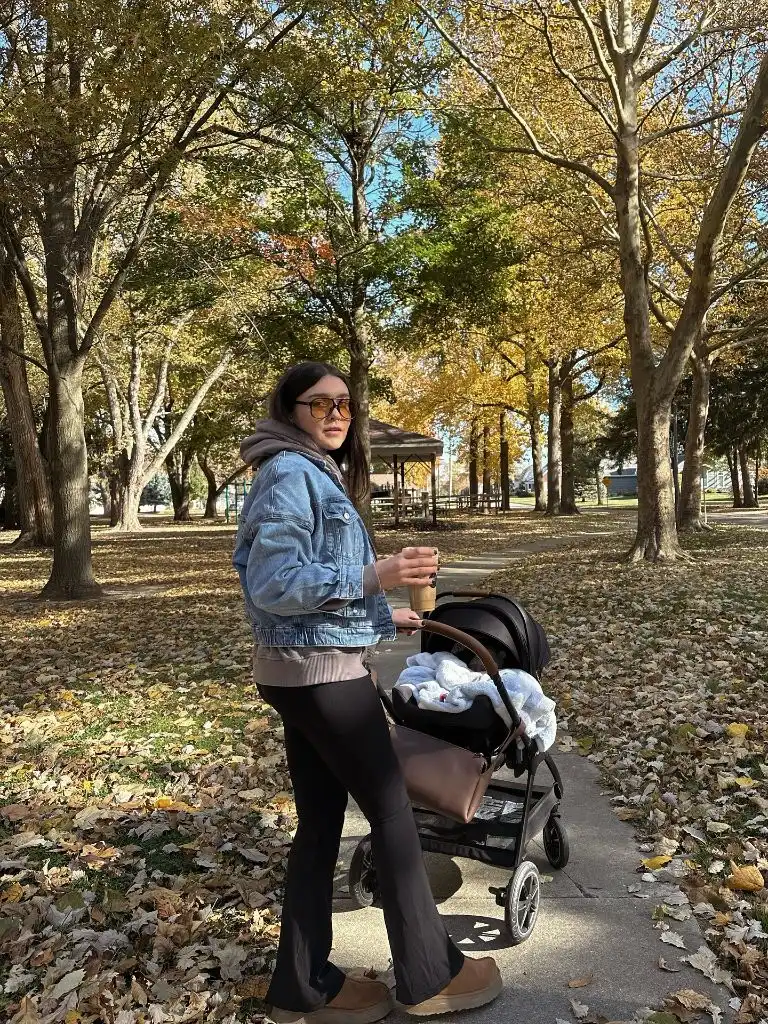 Mom with stroller in park wearing denim jacket and hoodie